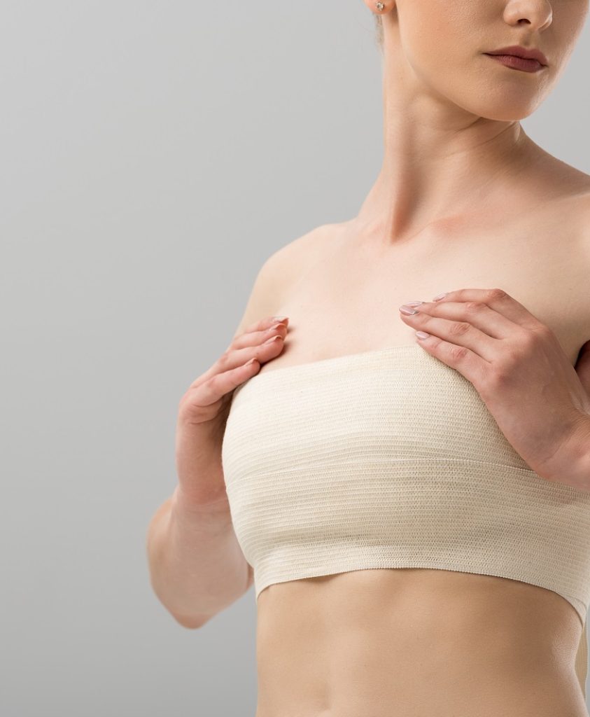 cropped view of woman with breast bandage isolated on grey
